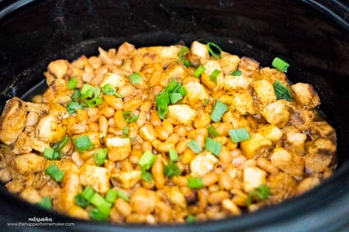 A crockpot filled with white chicken chili topped with green onion