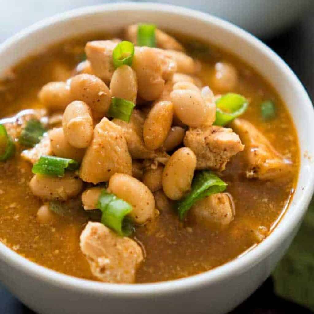 A close up of white chicken chili topped with green onion