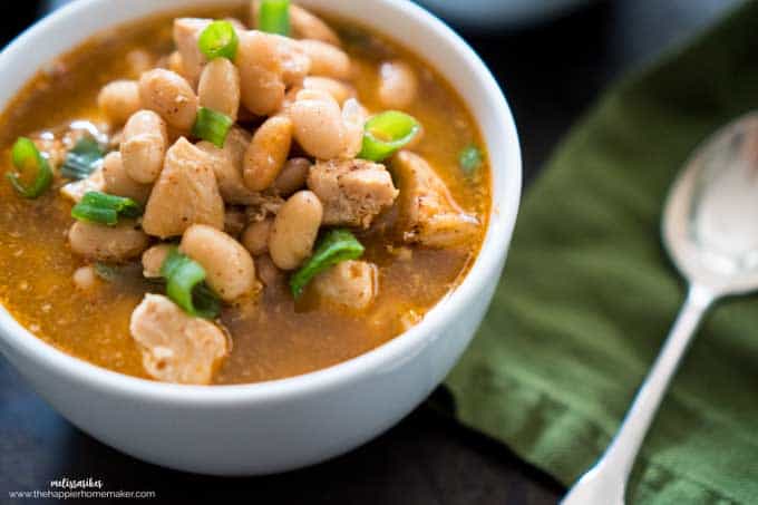 A close up of white chicken chili topped with green onion