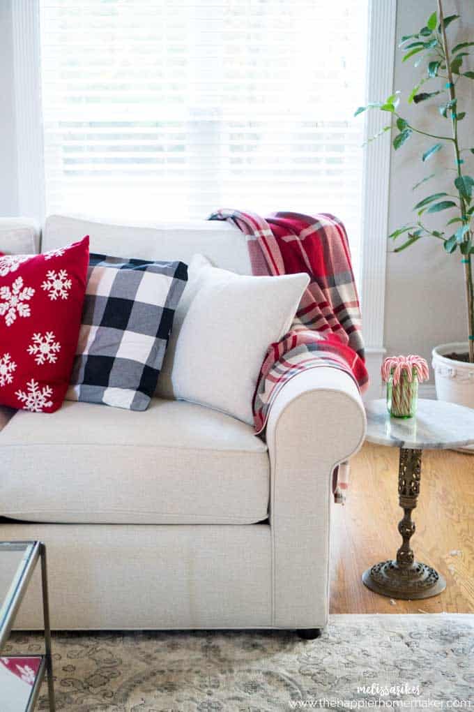 A white sofa with a buffalo check throw and assorted throw pillows