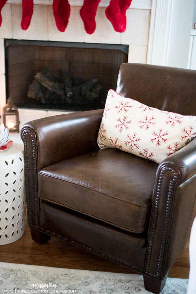 A brown leather chair with a decorative red snowflake pillow 