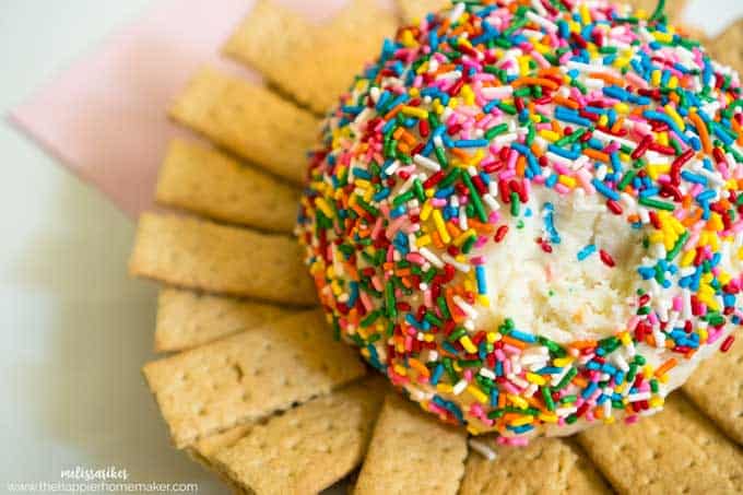 A close up of a cheesecake ball with sprinkles and crackers surrounding it