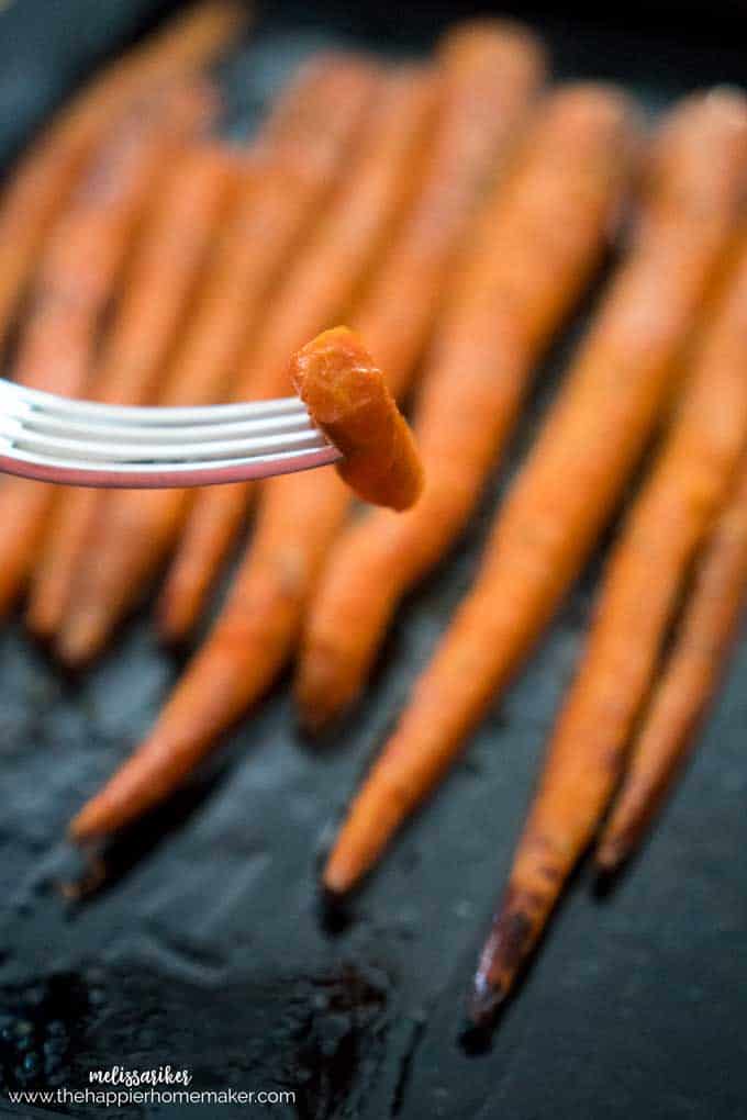 A close up of a bite of carrot on a fork after being roasted