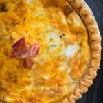 A close up a baked quiche garnished with bacon
