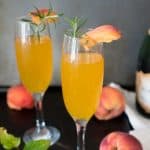 Two Bellini and Champagne cocktails garnished with a peach and rosemary