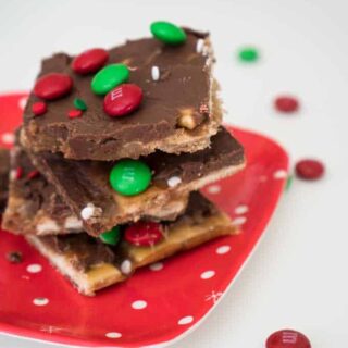 A close up of saltine cracker toffee with red and green M&Ms