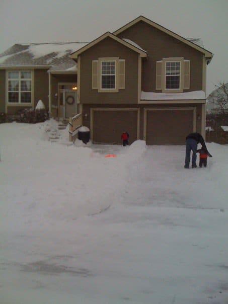 A house covered in snow with family out front