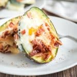 Baked Eggs and Avocado with Bacon and Cheese on a white plate