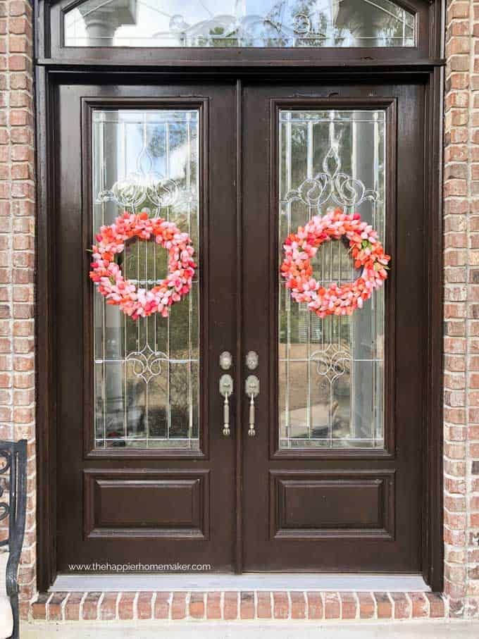 large double wood doors with each holding a pink wreath of tulips