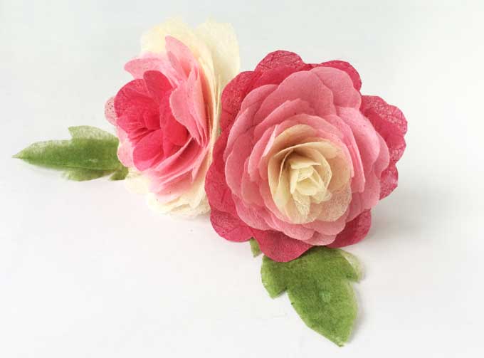 A close up of two pink and white tissue paper flowers