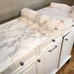 white rolling kitchen island with top being covered in marble contact paper