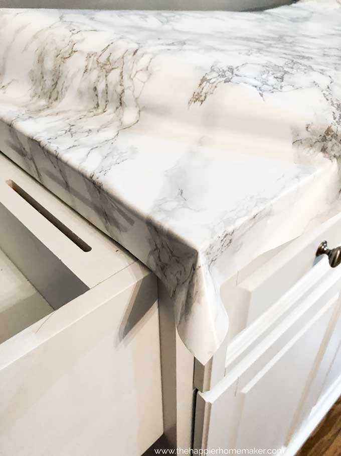 close up of edge of counter being covered in marble contact paper