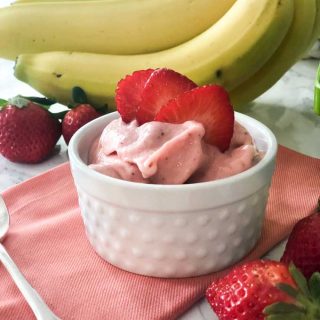 strawberry banana ice cream in white hobnail ramekin with sliced strawberry garnish