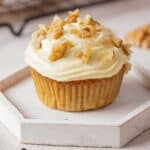close up of carrot cake muffin with cream cheese frosting and chopped walnuts
