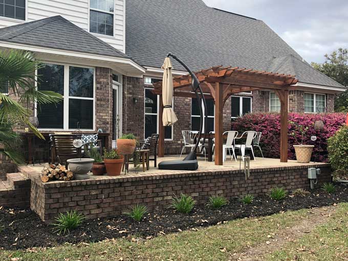 large raised patio with cedar pergola and patio furniture