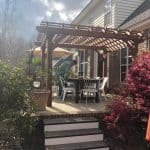 raised patio with large wooden pergola and dining set