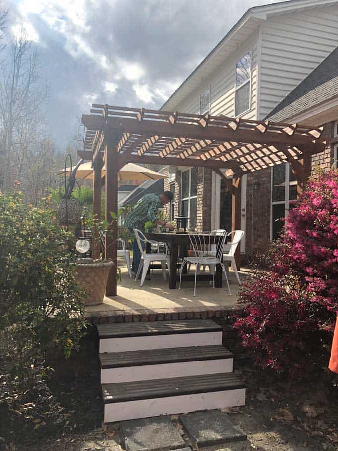 raised patio with large wooden pergola and dining set