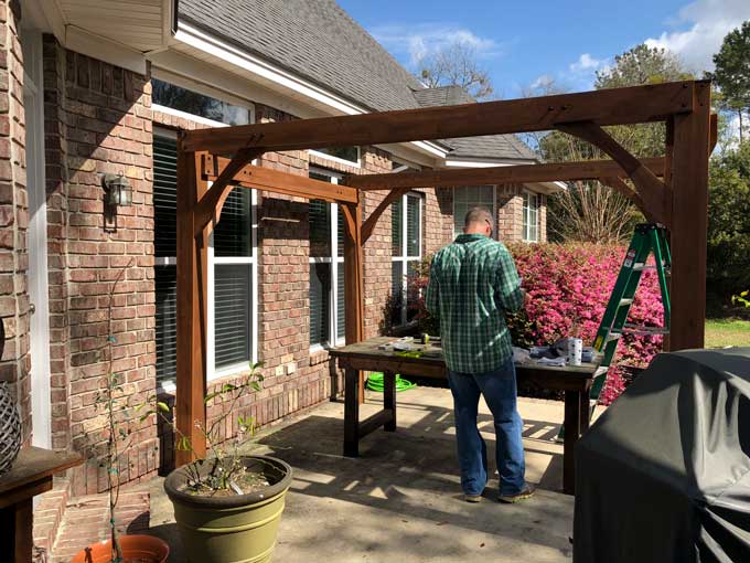 A man sitting with a half assembled pergola on patio