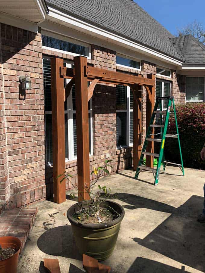 pieces of a pergola leaning against a brick home