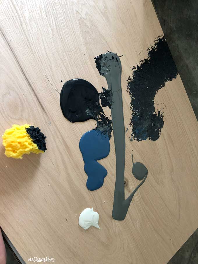 sponging blue and gray and black paints on piece of wood
