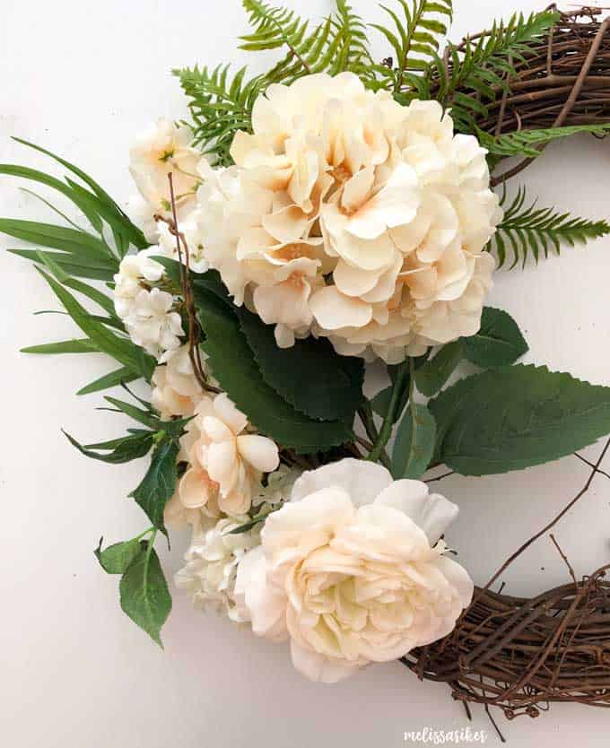 peach flowers and greenery on grapevine wreath