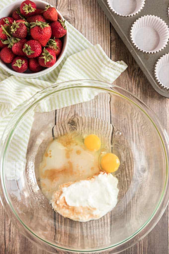 glass bowl with cracked eggs and sugar