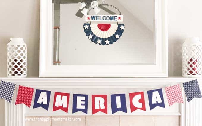 banner spelling America in red white and blue on white mantel with mirror over it