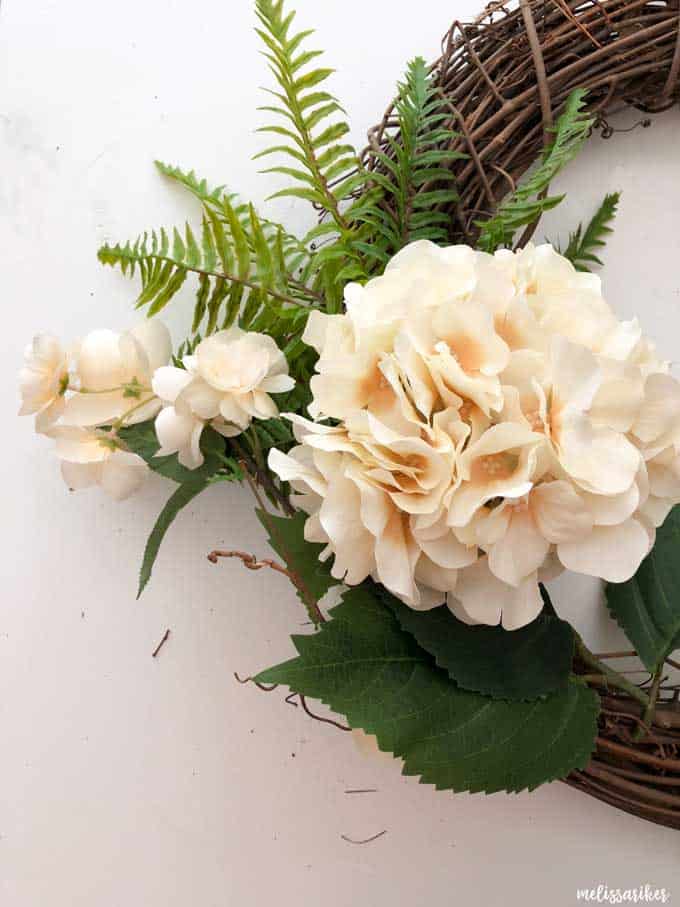 A close up of a fake flower on a grapevine wreath