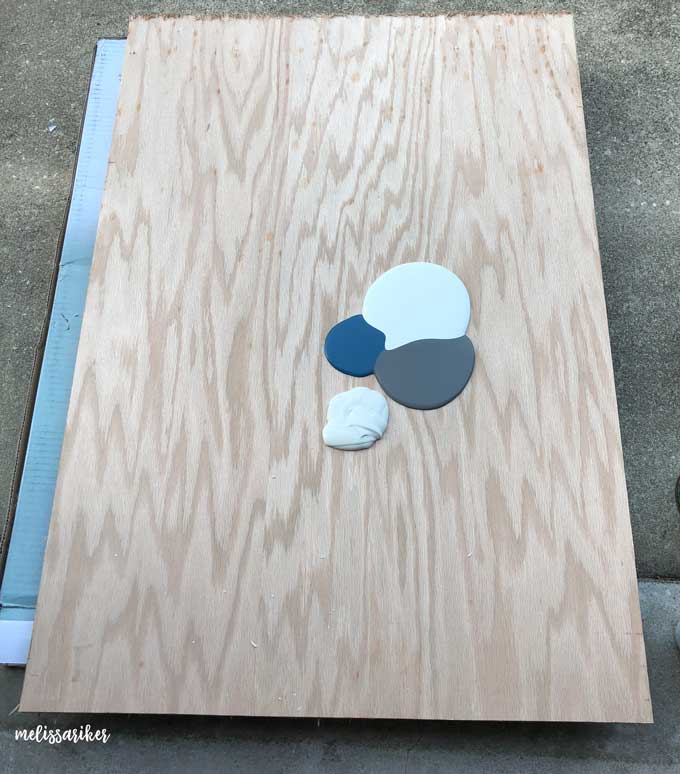 puddles of blue and gray paints on large piece of wood