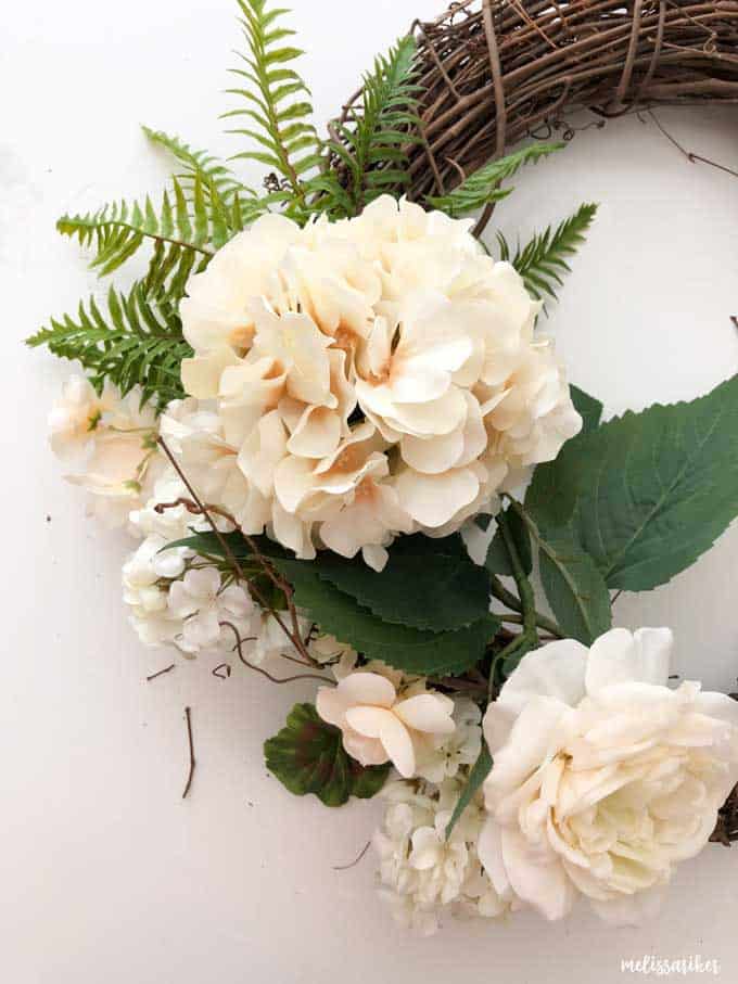 A close up of a faux flower on a grapevine wreath