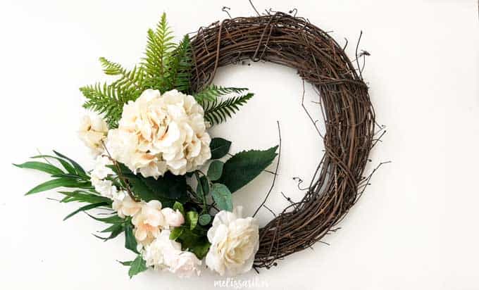 grapevine wreath with fake ferns and white flowers