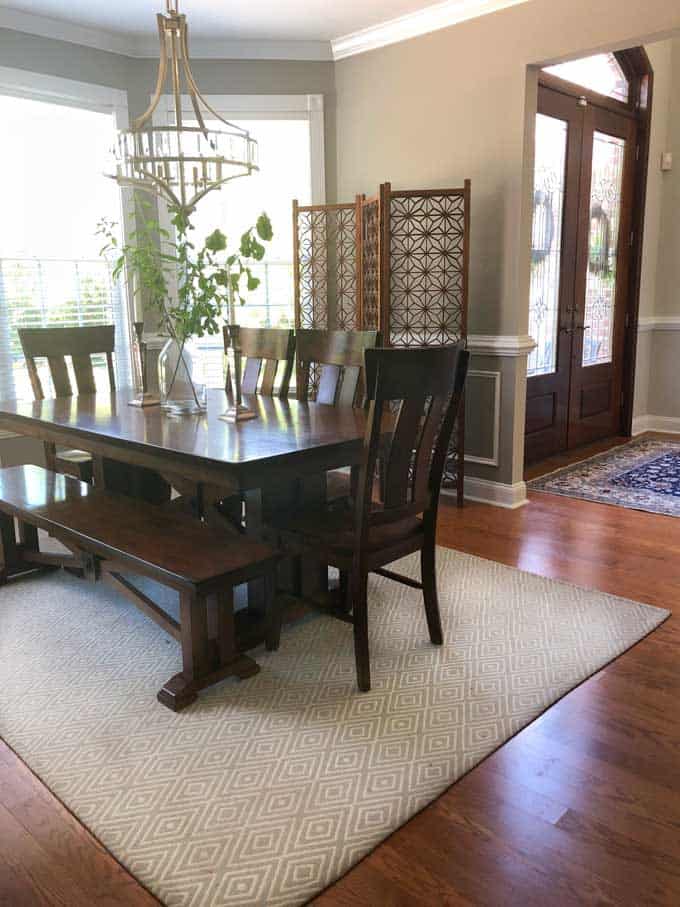 A dining room table with wood screen in background