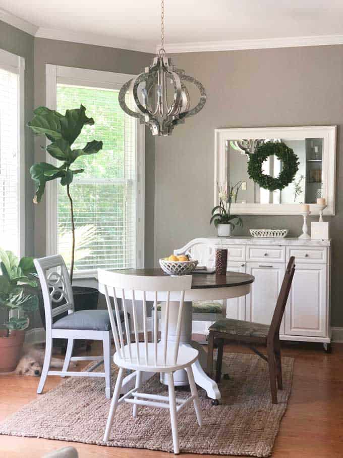 A dining room table with mismatched chairs and modern light fixture