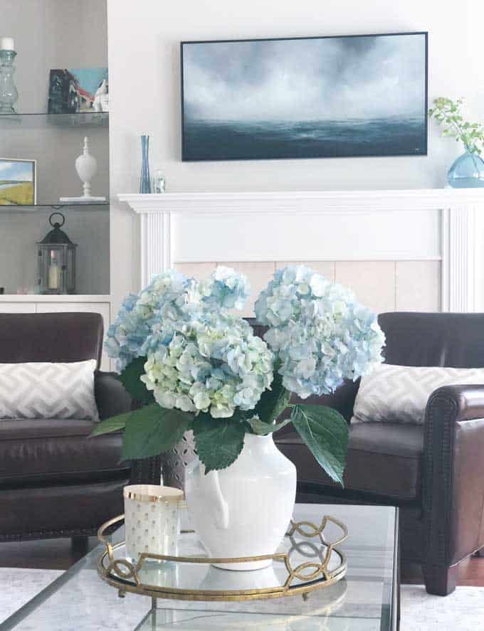 A living room filled with furniture and vase of blue hydrangeas on a table