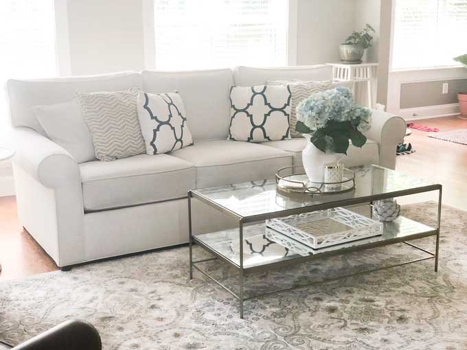 A living room filled with white couch and gold and glass coffee tables