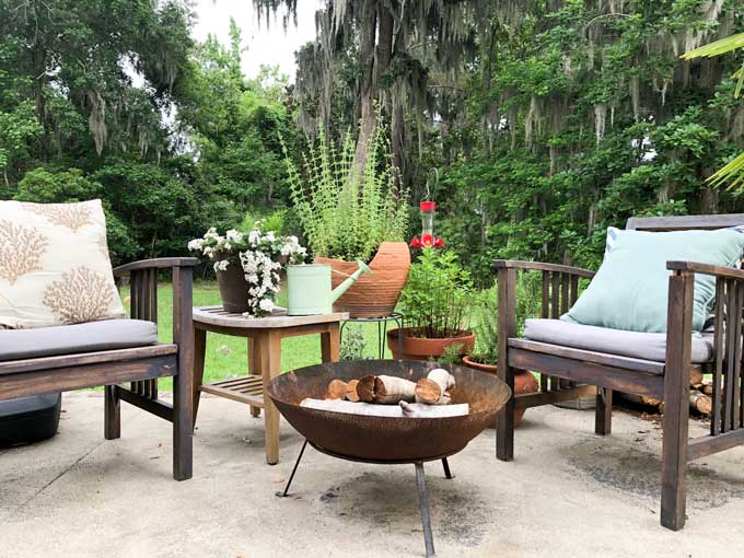 metal fire pit with wood chairs and plants on outdoor patio