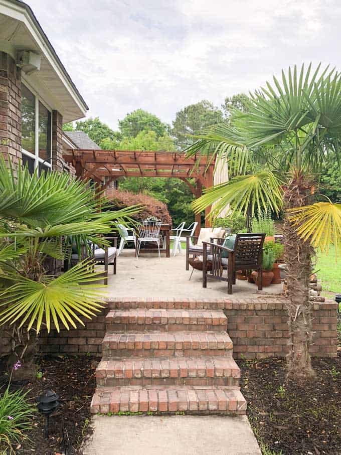 patio with brick trim and palm trees on either side of stairs