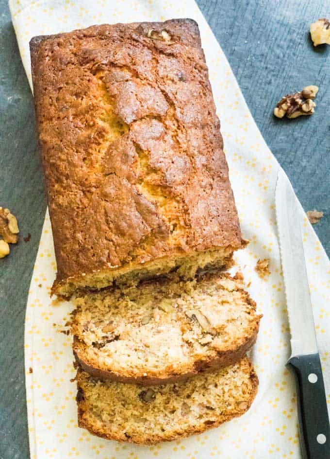 overhead view of walnut banana bread on cutting board with two slices cut