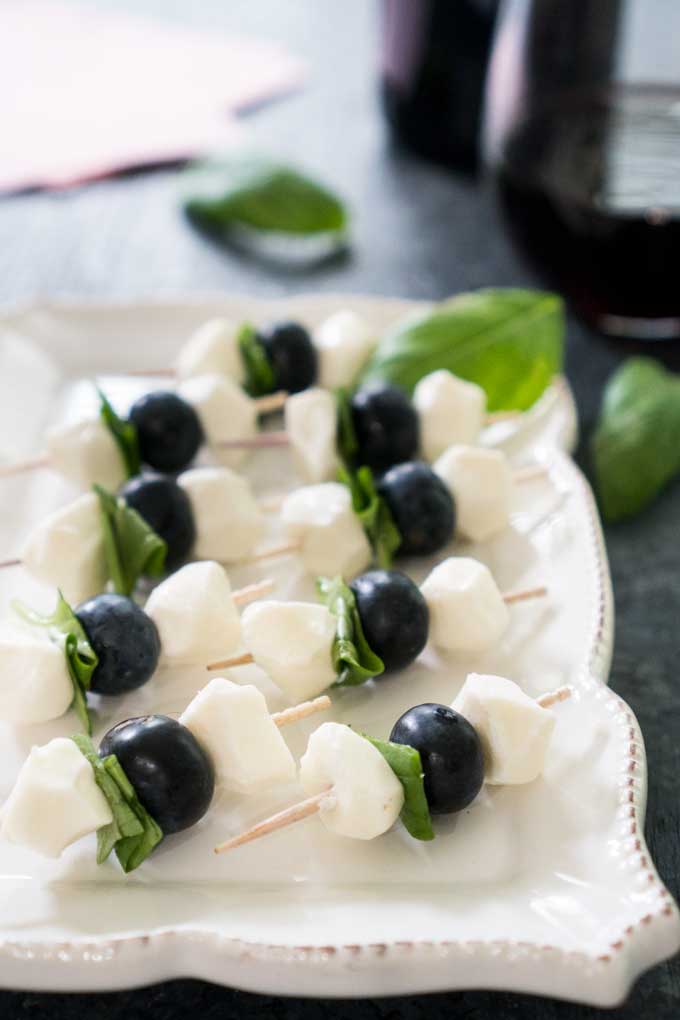 toothpicks with small mozzarella balls, blueberries, and folded basil 