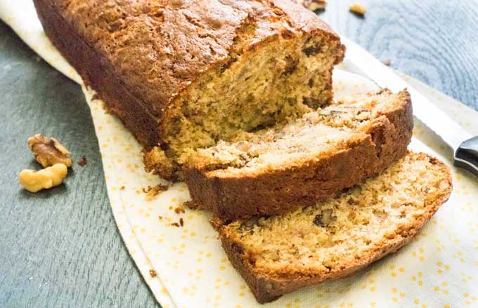 walnut banana bread on cutting board with two slices cut