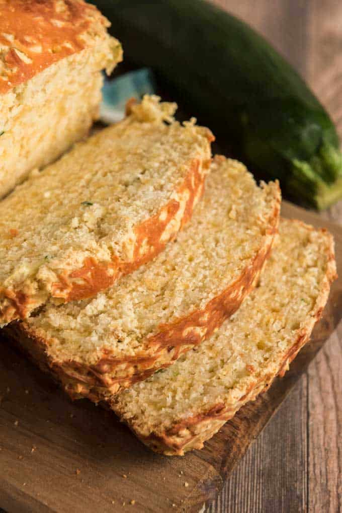 close up of sliced cheddar zucchini bread with whole zucchini next to it