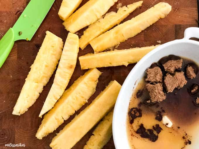 spears of pineapple with bowl of brown sugar 