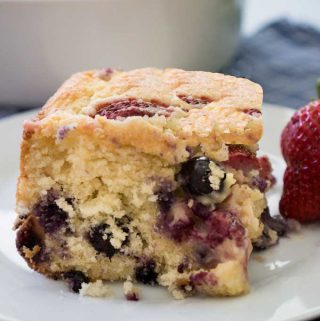 A piece of berry buttermilk cake on a white plate