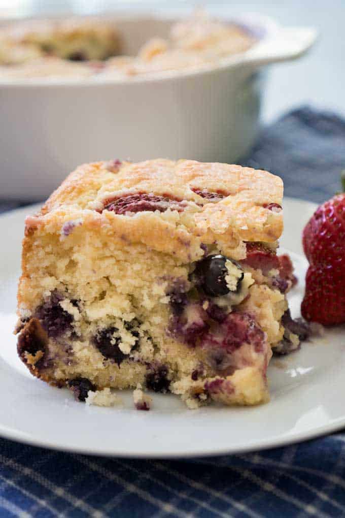 A piece of berry buttermilk cake on a white plate