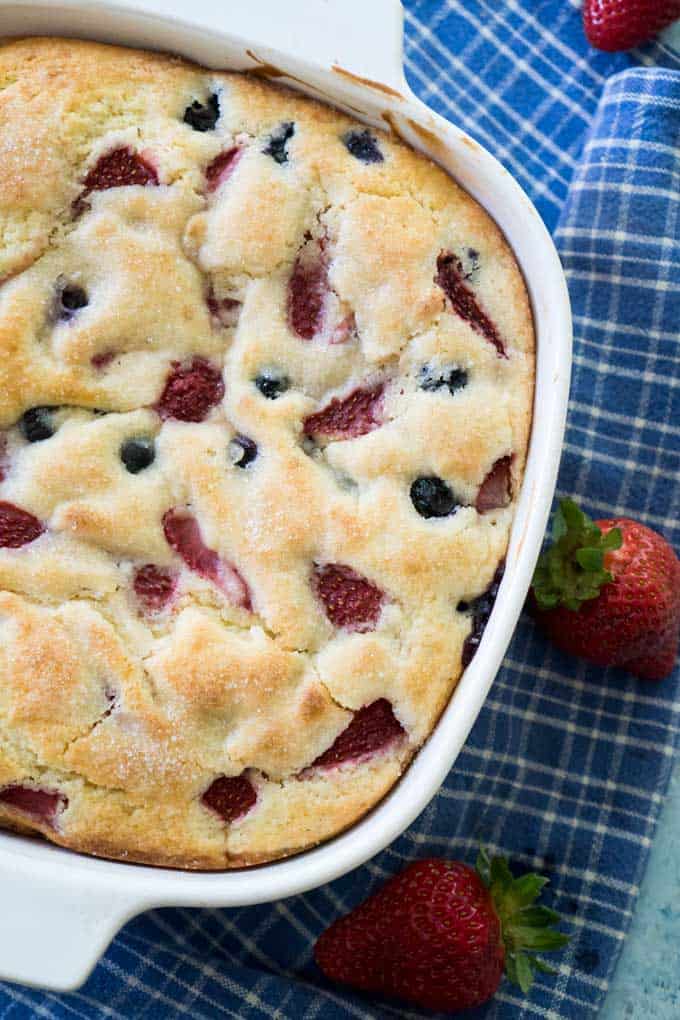 close up overhead view of berry buttermilk cake in white casserole dish