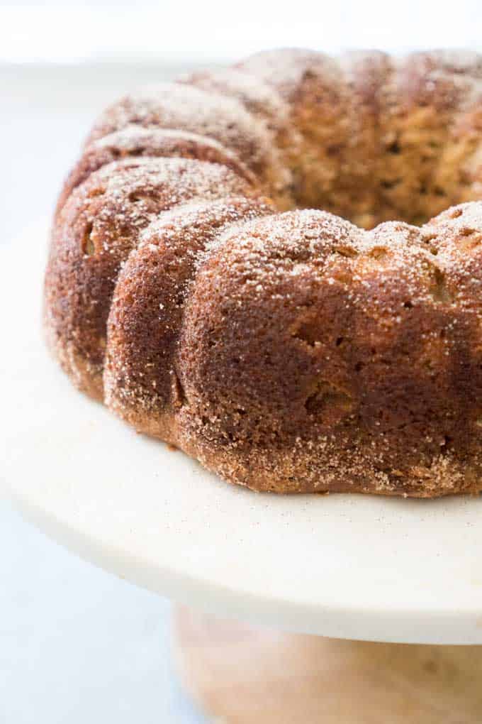 A close up of an Apple Cinnamon bundt cake on white cake stand