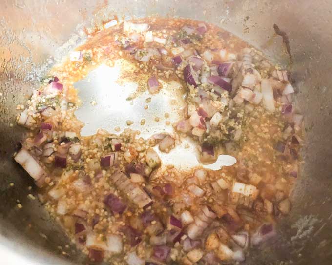 A close up of  onion, garlic, and broth simmering in pan