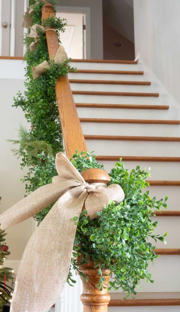 a stair case with fake vine hung up and a bow