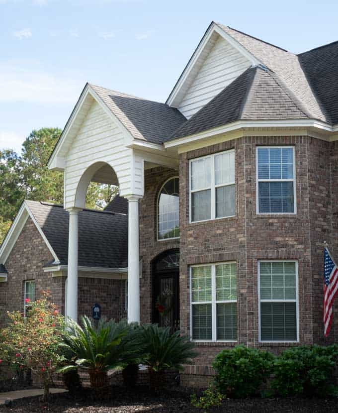 large brick home with arched entry with columns