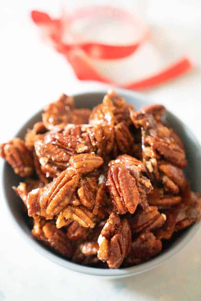 Spicy Candied Pecans close up in bowl with ribbon in background